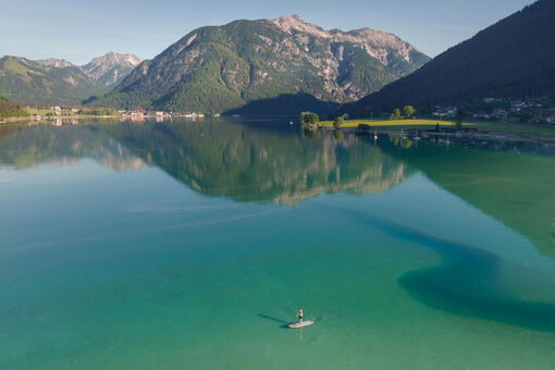 Standup paddle boarding along the southern shore of Lake Achensee, backdropped by the Seeberg and the Seekar.